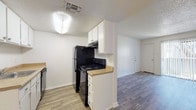 This single-floor unit offers a practical and well-organized layout, finished throughout with durable wood-style flooring that lends a cohesive, modern look to every room. The living area is bright and open, featuring a textured ceiling and a front entry door that connects seamlessly to the rest of the unit. An adjacent hallway leads to the kitchen and bedrooms, creating an efficient flow throughout the space.

The galley-style kitchen is thoughtfully equipped with white cabinetry above and below the counters, light-toned laminate countertops, a single-basin sink, a black electric range, a black refrigerator, and a dishwasher. A ventilation hood is mounted above the range, and the layout maximizes storage and workspace along both walls.

The two bedrooms each feature wood-style flooring and ceiling fans with light fixtures. One bedroom includes a window with blinds that brings in natural light, while the other connects to a generously sized walk-in closet outfitted with built-in shelving and hanging rods on multiple walls.

Both bathrooms are finished with wood-style flooring and include a full tub-and-shower combination with white tile surrounds, a toilet, and a vanity with a granite-style countertop and white cabinetry. The primary bathroom also features a large mirror above the vanity. Clean white walls and textured ceilings are consistent throughout, creating a neutral, move-in-ready environment.