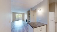 This thoughtfully designed 1-bedroom, 1-bathroom residence offers a functional and comfortable single-floor layout. The open-concept living and kitchen area serves as the heart of the home, where light gray wood-style flooring flows seamlessly throughout. The living room is highlighted by a classic brick fireplace flanked by built-in shelving, providing both character and storage. A large sliding glass door opens to a private balcony, flooding the space with natural light and offering pleasant views of surrounding greenery.

The kitchen features white shaker cabinetry, granite-style countertops, a subway tile backsplash, and white appliances including a refrigerator, dishwasher, and range. An in-unit washer is also conveniently located within the kitchen area. A granite-topped peninsula provides additional prep space and visual connection to the living area.

The bedroom is a comfortable, well-proportioned retreat with its own sliding glass door and balcony access, continuing the natural light theme found throughout the home. The full bathroom is cleanly finished with a tiled tub-shower combination, white cabinetry with granite countertops, and wood-style flooring. Two hallways connect the rooms efficiently, completing this practical and inviting layout.