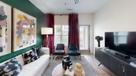 Located at 207 Gresham Ln in Mooresville, NC, this single-floor residence showcases a thoughtfully curated interior design that blends bold color palettes with contemporary finishes throughout. The layout flows naturally across wood-look flooring that unifies each space with warmth and continuity.

The kitchen is a standout, featuring dark cabinetry paired with crisp white countertops, stainless steel appliances including a side-by-side refrigerator, and a central island with pendant lighting overhead. It opens seamlessly into the dining area, creating an ideal space for entertaining.

The living room commands attention with a deep emerald green accent wall, large windows dressed in rich burgundy velvet drapes, and abundant natural light. Abstract artwork and layered textiles contribute to a sophisticated, gallery-like atmosphere.

The bedrooms each carry a distinct personality. One features bold black-and-white patterned wallpaper and a four-poster bed frame. Another showcases deep green walls and an upholstered canopy headboard flanked by arched mirrors and sculptural nightstand lamps. A third offers a more neutral palette with a brass four-poster frame and natural wood accents.

The bathrooms are finished with white tile, dark hardware, and walk-in glass showers or tub-shower combinations, with one featuring a walk-in closet.