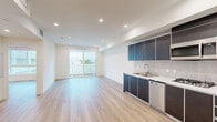 Located in the heart of Los Angeles' Fairfax district, this modern 1-bedroom, 1-bathroom unit at 951 Ogden Ave offers a thoughtfully designed open-concept layout finished with light hardwood flooring throughout. The combined kitchen and living area creates a seamless, airy space bathed in natural light, with sliding glass doors opening to a private balcony that frames views of the surrounding neighborhood. The kitchen is well-appointed with dark cabinetry accented by silver trim, white countertops, a tiled backsplash, and a full suite of stainless steel appliances including a refrigerator, dishwasher, gas cooktop, and over-range microwave. Recessed lighting illuminates the entire unit with a clean, modern aesthetic. The generously sized bedroom features a mirrored sliding-door closet and a large window that fills the room with natural light. The bathroom is outfitted with a combined tub and shower enclosed by sliding glass doors, chevron-patterned tile, a wall-mounted sink, and a mirror. A dedicated in-unit laundry area adds everyday convenience. Clean white walls and a bright, neutral palette give the space a fresh, contemporary feel throughout.