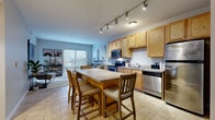 Located at 205 Vine St in Columbus, OH, this one-bedroom, one-bathroom unit offers a well-organized single-floor layout that maximizes every square foot. The open-concept kitchen and living area serves as the heart of the space, featuring light maple cabinetry, a white subway tile backsplash, stainless steel appliances including a range, microwave, and dishwasher, and a dining table with bar-height seating. Track lighting illuminates the kitchen, which flows seamlessly into the living room. The living area is bright and airy, benefiting from large windows and a sliding glass door that invites natural light and provides access to an outdoor balcony with exterior views. Neutral-toned tile flooring runs throughout the kitchen and living spaces, transitioning to plush carpet in the bedroom. The bedroom features a tray ceiling that adds architectural interest, a large sliding glass door with balcony access, and a walk-in closet. The bathroom is well-appointed with a dual-sink vanity, warm wood cabinetry, a large mirror with overhead lighting, and a glass-enclosed walk-in shower. A dedicated hallway and closet provide additional storage, completing this efficiently designed and comfortable urban residence.