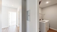 Located at Jefferson Ridge Drive in Jeffersonville, Indiana, this 2-bedroom, 2-bathroom residence offers a thoughtfully designed single-floor layout. The open-concept living, dining, and kitchen area serves as the heart of the home, bathed in natural light from large windows. The kitchen is well-equipped with white shaker-style cabinetry extending to the ceiling, granite-look countertops, stainless steel appliances including a range, microwave, and refrigerator, and durable wood-look flooring that flows throughout the main living areas. Both bathrooms mirror the kitchen's refined aesthetic, featuring white vanity cabinetry with granite countertops, undermount sinks, and wood-look flooring. The two bedrooms offer comfortable proportions; the primary bedroom includes a ceiling fan, multiple windows that invite natural light, and hardwood-style flooring, while the second bedroom features plush carpet and a generous window with exterior views. Four closets provide ample storage throughout. A dedicated laundry room houses a full-size washer and dryer with overhead wire shelving. The hallway connects all spaces efficiently, and a recessed electrical panel is conveniently integrated into the corridor wall, completing this functional and modern residence.