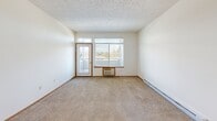 Located at 5317 Palouse Hwy in Spokane, WA, this 2-bedroom, 2-bathroom unit offers a well-organized single-floor layout designed for comfortable everyday living. The open-concept living room features plush carpeting, a textured ceiling, and large windows with a sliding door that invite natural light and provide pleasant views of surrounding greenery. Baseboard heating is present throughout the unit. The kitchen is efficiently laid out with warm wood-toned cabinetry, a white appliance package including a refrigerator, range, and microwave, and a raised breakfast bar that connects seamlessly to the living area. Hardwood-style flooring runs through the kitchen and entryway, creating a clean contrast to the carpeted living spaces. Both bedrooms are carpeted and well-lit by windows overlooking mature trees. The primary bedroom features a spacious walk-in closet outfitted with wire shelving, while the second bedroom includes a sliding double-door closet. Each bathroom is equipped with a full tub-shower combination, wood-toned cabinetry, and hardwood-style flooring. The unit's clean, neutral palette and functional design make it a practical and inviting home in a convenient Spokane location.