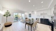 Located at 3910 Chapman St in San Diego's Ocean Beach neighborhood, this single-floor unit showcases a thoughtfully designed interior with a clean, contemporary aesthetic. Light wood-tone flooring flows throughout, complementing the crisp white walls and recessed lighting that brighten every room.

The open-concept living, dining, and kitchen area forms the heart of the space. The kitchen is outfitted with two-tone cabinetry—white uppers and deep navy lowers—paired with stainless steel appliances, including a refrigerator, dishwasher, microwave, and range. A wall-mounted split air conditioning unit provides efficient climate control. The dining area accommodates a full-sized table, while the living area connects directly to a private balcony through sliding glass doors, offering outdoor views of the surrounding neighborhood and palm trees.

The bedroom is a calm, light-filled retreat featuring sheer floor-to-ceiling curtains, light wood flooring, and a warm, neutral palette. A wall-mounted mini-split unit ensures year-round comfort.

The bathroom features marble-tiled walls surrounding a full shower-tub combination, a clean white vanity, and a distinctive slate-gray door, adding a modern architectural detail to the space.