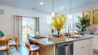 This single-story home is designed with an open-concept layout that seamlessly connects the kitchen, dining, and living areas, creating a bright and cohesive living environment. The kitchen serves as the centerpiece, featuring white shaker cabinetry, granite countertops, a large central island with bar seating and pendant lighting overhead, and a full suite of stainless steel appliances, including a gas range, built-in microwave, refrigerator, and dishwasher. A subway tile backsplash adds a clean, classic touch, while wood-look flooring runs throughout the main living areas. Large windows and a sliding glass door flood the space with natural light and provide views of the outdoors. The living room offers a comfortable, airy atmosphere with multiple windows and neutral tones. A dedicated dining area features a bold accent wall, grounding the space with visual interest. The bedroom includes plush carpeting and a ceiling fan, with an accent wall adding character. A full bathroom with a tub-shower combination and tile flooring completes the home. Overall, the space balances modern finishes with a warm, welcoming ambiance.