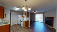 This single-floor 1-bedroom, 1-bathroom residence is designed for comfortable, efficient living. The living room serves as the heart of the home, featuring durable wood-look flooring, a textured ceiling, and a ceiling fan with integrated lighting. A corner fireplace with a wood mantel and brick hearth adds a warm, inviting focal point to the space. Large vertical-blind-covered sliding glass doors flood the room with natural light and provide access to an outdoor area.

The kitchen is thoughtfully laid out in a galley style, offering warm wood cabinetry, granite-look countertops, and white appliances including a refrigerator, electric range, and dishwasher. A skylight and overhead fluorescent lighting keep the space well-lit. A decorative chandelier marks the transition between the kitchen and the open living area, enhancing the connected feel of the floor plan.

The bedroom is a comfortable retreat, finished with plush wall-to-wall carpeting, a ceiling fan, a textured ceiling, and a window that brings in natural light. The bathroom includes a shower/tub combination and essential fixtures. Throughout the home, neutral gray walls and consistent flooring create a cohesive, move-in-ready aesthetic.