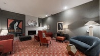 Located at 737 Lockefield Ln in Indianapolis, Indiana, this thoughtfully designed lounge space offers a sophisticated and welcoming atmosphere well-suited for relaxation and social gatherings. The single-floor layout is anchored by a classic white brick fireplace, which serves as a focal point along one wall and lends a sense of warmth to the entire room. Deep charcoal-gray walls provide a rich, modern backdrop that contrasts beautifully with the bold terracotta and white geometric-patterned carpet, giving the space a striking visual energy. Seating is both stylish and comfortable, featuring plush rust-red wingback chairs paired with a matching ottoman, a tufted dark accent bench, and a blue curved accent chair that adds a complementary pop of color. Carefully selected décor elements — including diamond-shaped mirrors, framed bird artwork, and sculptural table lamps — contribute to a curated, design-forward ambiance. A dark wood console table along the far wall provides additional display and surface space. Recessed ceiling lighting ensures the room is well-illuminated while maintaining its intimate character. Overall, the space strikes a refined balance between bold contemporary design and inviting comfort.