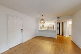 Located at 1299 SE Seventh Ave in Dania Beach, FL, this well-designed one-bedroom, one-bathroom unit offers a clean, modern aesthetic across its efficiently laid-out single floor. The open-concept living and dining area is bathed in natural light from sliding glass doors that lead to an outdoor view, complemented by light wood-style flooring and crisp white walls throughout. A textured ceiling adds character to the living space.

The kitchen features a peninsula with a white quartz countertop and an undermount stainless steel sink, white shaker-style cabinetry, a subway tile backsplash, and stainless steel appliances including a refrigerator and microwave. A stacked washer and dryer unit is conveniently tucked behind louvered doors adjacent to the kitchen.

The bedroom is carpeted for comfort and includes a ceiling fan, a dedicated closet, and a sliding glass door that opens to the outdoors, allowing ample natural light. The full bathroom is finished in white with a tub-shower combination, a single vanity with a large mirror, and wood-style flooring. A rattan pendant light in the living area adds a warm, coastal touch fitting for this South Florida location.