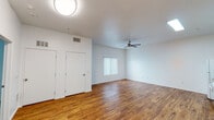 This single-floor unit offers a clean, functional layout designed for comfortable everyday living. The open living area is a standout feature, showcasing rich hardwood-style flooring that extends throughout the main spaces. A ceiling fan with a light fixture keeps the room comfortable year-round, while vertical blinds on the window allow for adjustable natural light. Ample closet storage is conveniently located within the living area.

The kitchen is well-equipped with light wood cabinetry, generous counter space, and white appliances including a full-size refrigerator and an electric range with overhead ventilation. The hardwood-style flooring continues seamlessly into this space, reinforcing a cohesive aesthetic.

The bathroom is thoughtfully designed with accessibility in mind, featuring stainless steel grab bars surrounding a walk-in shower stall, a vanity with matching light wood cabinetry, and hardwood-style flooring. The bedroom offers a quieter, softer feel with wall-to-wall carpeting and a window dressed with vertical blinds that invite natural light.

An additional multi-purpose room with a utility sink and access to both the bathroom and bedroom provides flexible living options. Throughout the unit, crisp white walls and consistent finishes create a bright, neutral backdrop ready for personalization.