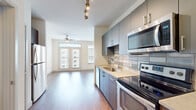Located on Martin Luther King Jr. Drive in Atlanta's Grant Park neighborhood, this single-floor residence offers a well-designed layout with modern finishes throughout. The open-concept kitchen is outfitted with a full suite of stainless steel appliances, including an electric range, over-the-range microwave, dishwasher, and a large refrigerator. Cabinetry in warm wood tones and cool gray-blue hues lines the kitchen walls, complemented by light quartz countertops and a classic subway tile backsplash. Track lighting above the kitchen adds a stylish, functional touch.

The living area extends naturally from the kitchen and is bathed in natural light from large windows and a set of French doors that open to views of the surrounding neighborhood. Light hardwood-style flooring runs throughout the main living spaces, and a ceiling fan provides comfort year-round. The bedroom is generously sized, also featuring a ceiling fan, multiple windows, and wood-style flooring. A spacious walk-in closet with wire shelving provides ample storage. The bathroom features large-format tile flooring, a soaking tub with subway tile surround, a wide vanity with a quartz countertop, and a well-lit mirror. In-unit laundry connections are also available.
