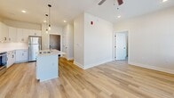 Located in the Shadow Creek community of Jackson, Tennessee, this single-floor residence offers a clean, modern design with thoughtfully appointed spaces throughout. Light-toned luxury vinyl plank flooring runs continuously across the unit, creating a cohesive and easy-to-maintain foundation in every room.

The open-concept kitchen and living area serves as the heart of the home, where a kitchen island with a built-in sink and pendant lighting anchors the space. Stainless steel appliances and white cabinetry complete the kitchen, which flows seamlessly into the main living area. Ceiling fans are installed throughout, enhancing comfort and airflow.

Each bedroom is generously proportioned, featuring large windows with blinds that invite ample natural light and offer views of the surrounding neighborhood. The bedrooms include dedicated ceiling fans, adding to the functional design.

The bathrooms are finished with white subway tile tub-and-shower surrounds, dark-toned vanities with white countertops, framed mirrors, and light wood-style flooring that ties into the rest of the unit. At least one walk-in closet is present, equipped with wire shelving and hanging rods for efficient storage. The overall palette of soft neutral walls, white trim, and black hardware finishes gives the space a crisp, contemporary feel.