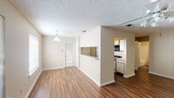 This single-story 2-bedroom, 2-bathroom residence offers a practical and comfortable layout designed for everyday living. The living room serves as the heart of the home, featuring rich hardwood-style flooring, a ceiling fan with light fixture, and a large window that invites ample natural light. A glass-paneled front door adds to the bright, welcoming atmosphere.

The open dining area flows seamlessly from the living space, highlighted by a pendant light fixture and a pass-through window that connects directly to the kitchen. The galley-style kitchen is efficiently arranged with white cabinetry, a gas range, dishwasher, refrigerator, and a window above the sink for additional natural light. Hardwood-style flooring continues throughout the kitchen.

Both bedrooms are generously proportioned, carpeted for comfort, and feature windows with blinds that provide natural light and privacy. Each room offers a calm, neutral palette with textured ceilings throughout the home.

The two bathrooms are clean and functional. The full bathroom includes a single-sink vanity with white countertop, a tub-shower combination, and hardwood-style flooring. The second bathroom provides convenient access from the bedroom area. This well-maintained residence combines practical design with comfortable living spaces throughout.