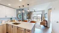 Located in the heart of downtown Fort Worth, this thoughtfully designed one-bedroom, one-bathroom residence offers a sleek, modern aesthetic throughout. The open-concept kitchen and living area serves as the centerpiece of the space, where a quartz-topped island with bar seating flows effortlessly into the living room. The kitchen is appointed with stainless steel appliances, two-tone cabinetry combining white upper cabinets with warm wood-toned lower cabinets, a tile backsplash, and globe pendant lighting that adds a stylish focal point overhead. Wide-plank hardwood flooring runs throughout the main living areas, lending warmth and continuity.

The living room is bathed in natural light from expansive floor-to-ceiling windows and a sliding glass door that opens to a private balcony overlooking the Fort Worth skyline. The bedroom continues this connection to the outdoors with its own large windows framing city views, complemented by a ceiling fan and ample space for a full furniture arrangement. The bathroom features large-format marble-look tile flooring, a dual-sink vanity with wood cabinetry and backlit mirrors, and direct access to a well-organized walk-in closet with custom shelving and hanging rods. An in-unit laundry area completes this efficient and stylish urban residence.