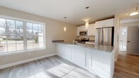 Located at 103 House St in Glastonbury, CT, this two-floor home offers a clean, modern design with consistent finishes throughout. The kitchen is a standout feature, centered around a large peninsula with granite countertops, white shaker-style cabinetry, stainless steel appliances including a refrigerator, range, and microwave, and pendant lighting overhead. Light-toned luxury vinyl plank flooring runs throughout the main living areas, complementing the neutral warm-beige wall tones and crisp white trim. Natural light flows generously through large double-hung windows.

The bathrooms are thoughtfully finished, featuring granite-topped white vanities, beige tile flooring, and white subway tile surrounds. One bathroom includes a tub-shower combination, while another offers a glass-enclosed walk-in shower. A half-bath with a window provides additional convenience on one of the floors.

The bedrooms are well-sized, each equipped with ceiling fans, generous closet space including double closets in at least one room, and large windows overlooking the surrounding greenery. A staircase with wood treads and a handrail connects the two floors. The attached garage provides substantial storage or parking space with an automatic opener and concrete flooring, completing this functional and well-designed home.