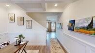 This two-story home in Athens, Alabama, offers six bedrooms and three bathrooms across two well-proportioned floors. The main level is anchored by a bright living area lined with multiple large windows dressed in neutral drapes, allowing abundant natural light to fill the space. A ceiling fan complements the airy atmosphere. The entry hallway features elegant coffered ceilings, wainscoting paneling, and hardwood-style flooring that flows throughout the home, creating a cohesive and polished aesthetic.

The kitchen is equipped with granite-speckled countertops, taupe shaker-style cabinetry, a stainless steel sink and dishwasher, and a window overlooking the exterior. A dedicated laundry room houses a full-size washer and dryer with overhead wire shelving for added storage convenience.

The upper floor contains the majority of the bedrooms, including a spacious primary bedroom with an en-suite bathroom featuring granite countertops and a walk-in closet with wire shelving. Additional bedrooms are bright and well-sized, each with hardwood-style flooring and natural light. A dedicated closet and hallway provide practical organization throughout. The home's clean white walls, modern fixtures, and thoughtful layout make it a functional and comfortable residence.