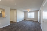 Located at 605 Suhtai Ct in Virginia Beach, Virginia, this single-floor residence offers a clean, modern aesthetic throughout its well-appointed layout. The open-concept living and dining area is anchored by rich, dark hardwood-style flooring and neutral-toned walls, with a ceiling fan overhead and ample natural light streaming through wide windows fitted with horizontal blinds. Track lighting adds a functional decorative touch to the living space.

The kitchen is thoughtfully designed with crisp white cabinetry, granite-look countertops, a stainless steel sink, and a full suite of stainless steel appliances including a refrigerator, electric range, and built-in microwave. A pass-through counter connects the kitchen to the main living area, enhancing the open flow of the space. Light wood-style flooring carries through the kitchen for a cohesive look.

The bedrooms feature plush wall-to-wall carpeting and bright windows that invite natural light. One bedroom includes a spacious reach-in closet with a bi-fold door and dedicated hanging storage. The bathroom is outfitted with a full soaking tub and shower surround featuring built-in shelving, complemented by brushed nickel fixtures.

A dedicated utility area houses an in-unit washer and a water heater, with overhead shelving for additional storage. The space combines practicality with contemporary finishes throughout.
