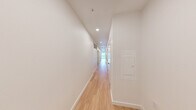 Located on the seventh floor at 1100 Boylston Ave in Seattle's Capitol Hill neighborhood, this modern two-bedroom residence offers a thoughtfully designed single-floor layout with a clean, contemporary aesthetic throughout. Light wood flooring runs seamlessly across every room, complementing the crisp white walls and creating a bright, cohesive atmosphere.

The spacious living area is a standout feature, bathed in natural light through large floor-to-ceiling windows that frame views of the surrounding Seattle cityscape. A tray ceiling adds architectural dimension to the room, while a wall-mounted mini-split unit ensures year-round comfort. The kitchen is equipped with stainless steel appliances, including a range and refrigerator, and features warm wood cabinetry that adds a touch of texture to the otherwise minimalist palette.

The generously sized primary bedroom offers ample space, enhanced by a high clerestory window that draws in additional natural light. The second bedroom is equally well-appointed and versatile. A dedicated closet provides practical storage, and a long, well-lit hallway with recessed lighting connects the rooms with a sense of flow and purpose. The bathroom is neatly integrated into the layout, completing this efficient and stylish urban residence.