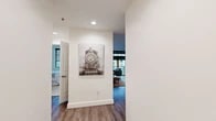 Located at 900 NW Lovejoy St, Unit 718 in Portland's vibrant Pearl District, this one-bedroom, one-bathroom residence offers a well-designed single-floor layout with a clean, modern aesthetic throughout. The open-concept living, dining, and kitchen area forms the heart of the unit, where warm hardwood-style flooring flows seamlessly underfoot. The living room is highlighted by floor-to-ceiling windows with access to a balcony, flooding the space with natural light and framing views of the surrounding cityscape. Built-in shelving adds functional character to the living area. The dining space is quietly tucked adjacent to the living room, offering an intimate setting for meals. The kitchen is well-appointed with rich wood cabinetry, granite countertops, stainless steel appliances including a range, microwave, and dishwasher, and a dedicated sink with ample counter space. The bedroom provides a comfortable retreat with plush carpeting, a large window with city views, and generous proportions. The bathroom features white cabinetry, granite countertops, a large vanity mirror, and a bright, clean finish. A welcoming entryway with recessed lighting and white panel doors completes this thoughtfully laid-out urban residence.