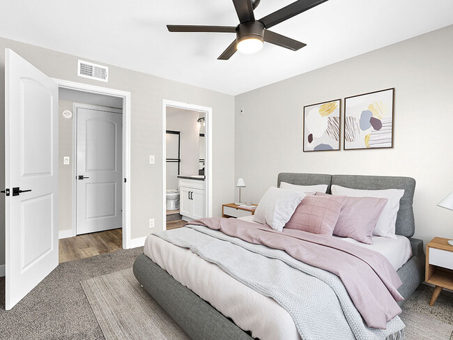 Carpeted bedroom with ceiling fan and private bathroom. - Woodridge Apartments