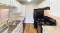 This single-floor residence offers a clean, well-maintained layout with a variety of functional spaces throughout. The living area serves as the heart of the home, featuring light gray laminate wood flooring, a ceiling fan with lighting, and a large sliding glass door fitted with vertical blinds that invites an abundance of natural light and provides views of the surrounding greenery outdoors.

The kitchen is equipped with rich, warm-toned wood cabinetry and granite countertops on both sides, creating an efficient workspace. A window above the counter allows natural light to filter in, brightening the cooking area.

Multiple bedrooms are finished with neutral-toned wall-to-wall carpeting and white panel doors, lending a comfortable and cohesive feel. Each room benefits from windows dressed with horizontal blinds, providing both natural light and privacy. Recessed and flush-mount ceiling fixtures provide ample overhead lighting throughout.

The bathroom area features light ceramic tile flooring, rich wood vanity cabinetry topped with granite countertops, and a separate water closet. A dedicated tub and shower combination completes the bathroom suite.

Throughout the space, clean white walls, consistent trim, and neutral finishes create a bright, move-in ready environment with a simple and practical aesthetic.