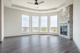 Located at Prairie Lakes Dr in Sun Prairie, WI, this 2-bedroom, 2-bathroom residence offers a thoughtfully designed single-floor layout with modern finishes throughout. The open-concept living area is a standout, anchored by a striking floor-to-ceiling stone corner fireplace and a curved tray ceiling that adds architectural character. A sweeping bank of large windows floods the space with natural light while framing panoramic views of the surrounding cityscape and landscape.

The kitchen flows seamlessly from the living area and features stainless steel appliances including a range, over-the-range microwave, and refrigerator, complemented by gray cabinetry and light countertops. A central island with a built-in sink and pendant lighting above makes the kitchen both functional and visually appealing. Wood-look flooring runs throughout the main living areas, while plush carpet adds comfort to the bedrooms.

The primary bedroom is generously sized with access to a dual-sink bathroom featuring gray vanity cabinetry and modern matte black fixtures. The second bedroom benefits from large windows with open views. Both closets include wire shelving systems for organized storage. A dedicated laundry room houses a full-size washer and dryer. A secondary living or flex space includes a wet bar and sliding door access to an outdoor area.