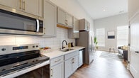 Located at 1206 N. 4th Street in Columbus, Ohio's vibrant Short North neighborhood, this thoughtfully designed single-floor unit maximizes every square foot with a smart, open layout and contemporary finishes. The combined kitchen and living area serves as the heart of the space, where soft grey shaker-style cabinetry with brushed gold hardware pairs elegantly with white subway tile backsplash and light quartz countertops. Stainless steel appliances, including a French door refrigerator, electric range, built-in microwave, and dishwasher, complete the well-appointed kitchen. Warm-toned luxury vinyl plank flooring flows seamlessly throughout, grounding the open-concept living zone, which benefits from soaring vaulted ceilings and multiple windows that flood the room with natural light. The bathroom features large-format marble-look porcelain tile flooring, a vanity with grey cabinetry and matte black hardware, and a full tub/shower combination with a sleek matte black fixture set. Additional conveniences include a dedicated closet for storage and a utility room. Clean white walls, high ceilings, and an abundance of natural light give this compact unit an airy, open ambiance throughout.
