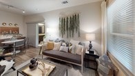 This well-appointed single-floor residence showcases a thoughtfully designed layout that balances modern aesthetics with functional living. The kitchen serves as a central highlight, featuring rich wood-toned cabinetry extending to the ceiling, a white quartz countertop island with bar seating, stainless steel appliances including a gas range and French door refrigerator, a subway tile backsplash, and wood-look flooring throughout. Industrial-style pendant lighting adds a contemporary touch overhead.

The living area is bright and inviting, benefiting from natural light through large windows and a glass door that opens to an outdoor space. Wood-look flooring continues here, grounding the room with warmth and cohesion.

The bedrooms are carpeted for comfort, each offering natural light through blinds-equipped windows and ceiling fans. Thoughtful wall sconce lighting adds a refined touch in the primary bedroom, which also features generous storage.

The bathrooms are finished with wood-look tile flooring, dark wood vanity cabinetry, and white quartz countertops. The primary bath includes a glass-enclosed soaking tub and shower combination with large-format wall tile, while the secondary bath offers a tub-shower setup with a curtain enclosure. Both bathrooms maintain a clean, contemporary palette throughout.