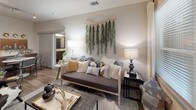 This well-appointed single-floor residence showcases a thoughtfully designed layout that balances modern aesthetics with functional living. The kitchen serves as a central highlight, featuring rich wood-toned cabinetry extending to the ceiling, a white quartz countertop island with bar seating, stainless steel appliances including a gas range and French door refrigerator, a subway tile backsplash, and wood-look flooring throughout. Industrial-style pendant lighting adds a contemporary touch overhead.

The living area is bright and inviting, benefiting from natural light through large windows and a glass door that opens to an outdoor space. Wood-look flooring continues here, grounding the room with warmth and cohesion.

The bedrooms are carpeted for comfort, each offering natural light through blinds-equipped windows and ceiling fans. Thoughtful wall sconce lighting adds a refined touch in the primary bedroom, which also features generous storage.

The bathrooms are finished with wood-look tile flooring, dark wood vanity cabinetry, and white quartz countertops. The primary bath includes a glass-enclosed soaking tub and shower combination with large-format wall tile, while the secondary bath offers a tub-shower setup with a curtain enclosure. Both bathrooms maintain a clean, contemporary palette throughout.
