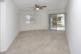 This single-floor, one-bedroom, one-bathroom residence offers a functional and comfortable layout designed to maximize everyday living. The living area features soft wall-to-wall carpeting, crisp white walls, and a ceiling fan overhead, creating a bright and airy atmosphere. A sliding glass door floods the space with natural light and opens to an outdoor view, while an additional window further enhances the sense of openness.

The galley-style kitchen is efficiently arranged with cream-toned cabinetry lining both sides, warm wood-look countertops, and hardwood-style flooring. A black electric range with overhead ventilation and a double sink provide all the essential cooking and prep amenities, with a doorway at the end leading further into the unit.

The bedroom continues the carpeted, light-filled theme, complete with its own ceiling fan, a window with vertical blinds, and a closet, offering a quiet and comfortable retreat.

The bathroom features hardwood-style flooring, a white vanity with countertop, a framed mirror with overhead lighting, and a combined shower and tub enclosure. The clean, neutral palette throughout the unit provides a cohesive and move-in-ready feel, making this a practical and inviting space.