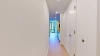 Located at 632 Newark Avenue in Jersey City, NJ, this modern 2-bedroom, 1-bathroom unit offers a clean, contemporary design throughout. Light wood-tone flooring runs seamlessly across the space, complementing the crisp white walls and recessed lighting that create a bright, airy atmosphere.

The galley-style kitchen is thoughtfully designed with flat-front gray cabinetry extending to the ceiling, white subway tile backsplash, quartz countertops, a stainless steel sink, and stainless steel appliances including a range and built-in microwave. Natural light flows in from a window at the end of the kitchen, enhancing its open feel.

Both bedrooms feature expansive floor-to-ceiling windows framed in sleek black, offering sweeping views of the Jersey City skyline and surrounding urban landscape. The generous natural light and open sightlines make each bedroom feel spacious and inviting. Sliding doors and ample closet space add functional storage throughout.

The bathroom is finished with large-format white wall tiles, a glass-enclosed walk-in shower, a floating vanity with modern fixtures, and an illuminated mirror cabinet. A dedicated in-unit laundry area adds everyday convenience. Hallways connect the rooms efficiently, maintaining a well-organized and flowing layout throughout this modern urban residence.