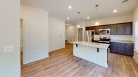 This single-floor residence in Lillington, NC offers a thoughtfully designed open-concept layout that seamlessly connects the living, dining, and kitchen areas. Light wood-look flooring flows throughout the main living spaces, complemented by neutral walls and recessed lighting that create a bright, welcoming atmosphere. Large windows fitted with blinds allow ample natural light to fill the rooms, with a glass door in the living area providing outdoor access to a balcony and views of surrounding greenery.

The kitchen is a standout feature, showcasing dark espresso cabinetry, granite countertops, and a suite of stainless steel appliances including a refrigerator, microwave, and range. A center island with pendant lighting and bar seating adds both functionality and style, making it an ideal space for casual dining or entertaining.

The bedrooms are carpeted for comfort and include ceiling fans, generous closet space, and a walk-in closet in the primary bedroom. The bathroom continues the cohesive design aesthetic with granite countertops, dark cabinetry, a large vanity mirror, and polished nickel hardware. The overall design is clean, modern, and move-in ready, reflecting a well-appointed and cohesive interior throughout.