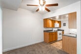This single-floor residence offers a well-organized and functional layout designed for comfortable everyday living. The open living and dining area is finished with plush wall-to-wall carpeting and features a ceiling fan with light fixture, providing a relaxed and airy atmosphere. A large window and sliding glass door allow natural light to fill the space and offer views of the surrounding greenery.

The galley-style kitchen is efficiently designed with warm honey-toned wood cabinetry, dark granite-look countertops, and tile flooring. It is equipped with a white gas range, built-in microwave, refrigerator, and a double sink, providing ample functionality. A breakfast bar peninsula opens the kitchen toward the main living area, enhancing the sense of connectivity throughout the home.

The bedrooms are generously sized, each carpeted and filled with natural light from large windows. One bedroom features a wide reach-in closet with a built-in rod for organized storage, while another offers outdoor views through slatted blinds. The bedrooms are accessible via a carpeted hallway.

The bathroom is clean and bright, featuring a full tub and shower combo with white tile surround, a wood-tone vanity with countertop, a toilet, and wood-look plank flooring. The space is finished with classic panel doors and gold-tone hardware throughout.