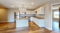 Located at 1011 30th St NW in Willmar, Minnesota, this single-floor, 4-bedroom, 2-bathroom home offers a well-designed layout with modern finishes throughout. The open-concept kitchen and living area serves as the heart of the home, featuring crisp white shaker cabinets, granite-style countertops, a central island with pendant lighting, recessed ceiling lights, and a full suite of stainless steel appliances including a refrigerator, electric range, microwave, and dishwasher. Wood-look luxury vinyl plank flooring flows seamlessly throughout the entire space, lending warmth and visual continuity to every room. The living area is bright and airy, with a sliding glass door that opens to an outdoor balcony, bringing in generous natural light and outdoor views. The four bedrooms are finished in neutral tones with the same durable flooring and offer ample wall space. The primary bedroom is comfortably sized. Both bathrooms are appointed with white vanities, large mirrors, tub-shower combinations, and stone-look tile flooring. Warm-toned wood interior doors add a classic touch throughout. A dedicated closet provides additional storage. The overall aesthetic is clean, contemporary, and move-in ready.