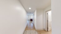 This thoughtfully laid-out one-bedroom, one-bathroom unit at 338 East 9th Ave in Homestead, PA offers a clean, modern living experience across a single floor. The interior is finished with light hardwood-style flooring throughout, crisp white walls, and recessed lighting that creates a bright and welcoming atmosphere.

The open-concept kitchen and living area serves as the heart of the unit. The kitchen features rich dark cabinetry, a granite-topped island with an integrated sink, stainless steel appliances including a full-size refrigerator, and a pendant light overhead. Multiple windows allow natural light to pour into the space, offering outdoor views of the surrounding neighborhood.

A well-proportioned entryway hallway leads into the main living area, providing a natural sense of arrival and flow throughout the unit. The bedroom is generously sized with its own large framed window that fills the room with natural light and outdoor greenery views. A standout feature is the stylish barn-style sliding door that opens to a dedicated walk-in closet complete with built-in shelving and hanging space.

The bathroom is clean and functional, equipped with a full walk-in shower with chrome fixtures and a crisp white surround. The overall design of this unit balances modern finishes with practical functionality, making it a comfortable and efficient living space.