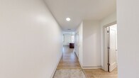 This thoughtfully laid-out one-bedroom, one-bathroom unit at 338 East 9th Ave in Homestead, PA offers a clean, modern living experience across a single floor. The interior is finished with light hardwood-style flooring throughout, crisp white walls, and recessed lighting that creates a bright and welcoming atmosphere.

The open-concept kitchen and living area serves as the heart of the unit. The kitchen features rich dark cabinetry, a granite-topped island with an integrated sink, stainless steel appliances including a full-size refrigerator, and a pendant light overhead. Multiple windows allow natural light to pour into the space, offering outdoor views of the surrounding neighborhood.

A well-proportioned entryway hallway leads into the main living area, providing a natural sense of arrival and flow throughout the unit. The bedroom is generously sized with its own large framed window that fills the room with natural light and outdoor greenery views. A standout feature is the stylish barn-style sliding door that opens to a dedicated walk-in closet complete with built-in shelving and hanging space.

The bathroom is clean and functional, equipped with a full walk-in shower with chrome fixtures and a crisp white surround. The overall design of this unit balances modern finishes with practical functionality, making it a comfortable and efficient living space.
