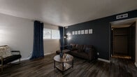Located at 2029 N Woodlawn St in Wichita, KS, this thoughtfully designed one-bedroom, two-bathroom unit offers a cohesive and contemporary living experience across a single floor. Wood-look flooring runs throughout, tying each room together with a warm, modern aesthetic.

The living room makes a strong first impression with a bold dark accent wall, textured ceiling, and a bright window dressed in rich navy curtains that allow natural light to filter in. An entryway area features sleek console furniture beneath a striking aviation-themed triptych, setting the tone for the space's recurring motif.

The galley-style kitchen is outfitted with slate-blue cabinetry, black appliances, and a double sink, maximizing functionality within a compact footprint. Adjacent to the kitchen, the dining area offers a cozy nook with a ceiling fan overhead and aviation-inspired wall décor adding character.

The bedroom is a comfortable retreat, featuring a window with natural light, matching navy curtains, and the same warm flooring found throughout the unit. Two closets provide ample storage.

Both bathrooms are finished with navy-blue vanity cabinetry and stone-look countertops. One bathroom includes a full shower-tub combination. The cohesive aviation theme and consistent color palette give this unit a distinctive, curated personality.