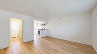 Located at 217 N Sunset Ave in West Covina, California, this efficiently designed single-floor unit offers a thoughtful layout across its cozy footprint. The living room serves as the heart of the space, featuring light-toned hardwood-style flooring, crisp white walls, and a textured ceiling that carries throughout the unit. A wall-mounted air conditioning unit and a large window with blinds allow for both climate control and natural light, creating a bright and airy atmosphere.

The kitchen opens directly to the living area via a peninsula counter with a warm wood-toned edge, promoting an open and connected feel. White cabinetry, a stainless steel range with overhead ventilation, and a sink with ample counter space make the kitchen both practical and clean in appearance. The seamless flow between the kitchen and living room maximizes the sense of space.

A dedicated closet provides convenient storage, while the bathroom is finished in an all-white palette featuring a vanity with under-cabinet storage, a combination tub and shower, a toilet, and a window with blinds that introduces natural light. The consistent use of light hardwood-style flooring and neutral tones throughout the unit creates a cohesive, clean, and functional living environment.