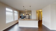 Located at 603 Rigsbee Ave in Durham, NC, this single-floor unit offers a well-designed, open-concept layout with a consistent blend of contemporary finishes throughout. The living area is bright and spacious, featuring rich dark hardwood-style flooring, large windows, and sliding glass doors that lead to a balcony, allowing abundant natural light to fill the space.

The kitchen is a functional centerpiece, equipped with stainless steel appliances including a refrigerator, electric range, and built-in microwave. Taupe cabinetry, granite countertops, a tile backsplash, and a large island with pendant lighting above complete the kitchen's modern aesthetic. The island provides additional workspace and serves as a natural divider between the kitchen and living area.

The bedrooms feature plush carpeting and windows with blinds that offer natural light and outdoor views. Ceiling fans are present in the bedrooms for added comfort. Two full bathrooms serve the unit; one includes a glass-enclosed shower with a granite-topped vanity, while the second features a tiled soaking tub, matching vanity, and light tile flooring throughout. The overall ambiance is clean, modern, and move-in ready.