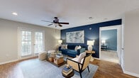 This thoughtfully designed 2-bedroom, 2-bathroom single-floor residence offers a cohesive and stylish living experience throughout its comfortable footprint. The living room immediately draws attention with a striking navy blue accent wall, rich hardwood-style flooring, a ceiling fan, and a glass-panel door that invites natural light. The open layout connects seamlessly to the dining area and kitchen, which features white shaker-style cabinetry, a subway tile backsplash, stainless steel appliances, a breakfast bar countertop, and continued hardwood-style flooring—ideal for both everyday living and entertaining. The primary bedroom is a generously sized retreat with plush carpeting, a ceiling fan, multiple windows for natural light, and a walk-in closet outfitted with wire shelving and ample hanging space. The second bedroom offers similar comfort and flexibility. Both bathrooms are finished with white cabinetry, clean countertops, and hardwood-style flooring, providing a bright, modern aesthetic. Additional highlights include a dedicated laundry area with a full-size washer and dryer, two closets for storage, and a textured ceiling throughout. The overall design palette of neutral tones accented with bold navy creates a polished and inviting atmosphere.