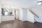 Located at 6400 Main St in Columbus, Georgia, this two-story home offers a well-organized layout with thoughtful finishes across both levels. The main floor features rich, dark hardwood-style flooring that flows through the open living and dining areas. A ceiling fan and elegant chandelier provide dual lighting options in the main living space, while a second chandelier illuminates the adjacent dining area. The kitchen is outfitted with dark shaker-style cabinetry, white countertops, stainless steel appliances, and a pass-through bar that connects to the dining area. Natural light filters in through a window overlooking greenery. A convenient half bathroom on the main floor includes dark wood cabinetry, a white countertop vanity, and hardwood-style flooring. The staircase leads to the upper level, where carpeted bedrooms provide a comfortable retreat. One bedroom features vaulted ceilings and a window framing outdoor greenery. The primary bedroom includes an en-suite bathroom with a glass-enclosed walk-in shower and marble-style tile surround. An additional full bathroom on this level offers a tub-shower combination with consistent dark cabinetry and white countertop finishes.