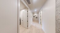 Located in Seattle's vibrant Belltown neighborhood, this thoughtfully designed 3-bedroom, 4-bathroom residence offers a refined modern aesthetic across a well-organized single-floor layout. Light-toned hardwood flooring flows through the main living areas and hallways, complemented by crisp white walls and a clean, minimalist palette throughout.

The kitchen is a standout feature, equipped with stainless steel double wall ovens, warm wood cabinetry, and dramatic floor-to-ceiling glass walls that open to a private balcony. The sweeping views of Puget Sound and the Seattle skyline are a defining characteristic of the living areas, with expansive glazing flooding the space with natural light.

Each bedroom is carpeted and generously proportioned, with the primary suite offering ample space and direct access to organized closet storage with built-in shelving and hanging rods. The bathrooms are finished with large-format tile, warm wood vanities, white quartz countertops, and matte black hardware — a consistent design detail found throughout the home. Select bathrooms include glass-enclosed walk-in showers.

A dedicated laundry room with in-unit washer and dryer adds everyday convenience. The hallways are bright and well-appointed, with recessed lighting and decorative wall accents completing the polished interior design of this high-rise Seattle residence.