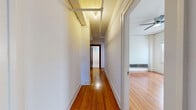 Located in the Westlake neighborhood of Los Angeles, this 2-bedroom, 1-bathroom unit at 2205 W 6th St blends classic architectural charm with functional living. Warm, honey-toned hardwood floors run throughout the living areas and bedrooms, lending a timeless character to each room. Ceiling fans are present in multiple rooms, adding to the comfortable, vintage aesthetic.

The living room is generously proportioned, with louvered closet doors and open sightlines that create an airy feel. A hallway connects the main living areas to the bedrooms and bathroom.

The spacious primary bedroom is a standout, featuring rich dark-wood-trimmed French doors that open to natural light, a large window, and a ceiling fan overhead. The second bedroom also benefits from natural light through multiple windows and includes a radiator for heating.

A dedicated walk-in closet with built-in shelving provides ample storage.

The kitchen is appointed with white cabinetry, glass-front upper cabinets, a stainless steel sink, gas range, and a classic black-and-white checkered tile floor, lending a retro yet clean aesthetic.

The bathroom features full white subway tile surrounds, a soaking tub, a pedestal sink, and a charming penny-tile mosaic floor, completing the unit's cohesive vintage character.