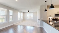 This well-appointed single-story home offers a thoughtfully designed layout with 3 bedrooms, 2 bathrooms, and 3 closets. The open-concept kitchen and living area serves as the heart of the home, featuring white shaker cabinetry with matte black hardware, dark granite countertops, a subway tile backsplash, and stainless steel appliances. Stylish pendant lighting hangs above the kitchen peninsula, adding a modern touch. Rich hardwood flooring flows through the main living and kitchen areas, while plush carpeting adds warmth to the living room and bedrooms. A built-in desk nook adjacent to the kitchen provides a convenient workspace. The spacious living room is filled with natural light from multiple windows and is equipped with a ceiling fan. Each bedroom features large windows with outdoor views, carpet flooring, and ceiling fans for comfort. The primary bedroom includes a generous walk-in closet with built-in shelving. The bathrooms are finished with large-format tile surrounds, soaking tubs, and matte black fixtures. Neutral gray tones throughout the home create a clean, cohesive aesthetic that is both modern and inviting.