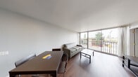 Located at 1709 Shattuck Ave in Berkeley, California, this single-floor unit offers a clean, modern aesthetic throughout. The open-plan living and dining area serves as the heart of the space, anchored by rich hardwood flooring and bathed in natural light from expansive floor-to-ceiling sliding glass windows that open to a balcony with views of the surrounding Berkeley neighborhood. The living area comfortably accommodates a seating arrangement and a dining table, creating a functional and inviting environment.

A hallway connects the main living space to the private quarters, lined with mirrored sliding closet doors that enhance the sense of openness. Two bedrooms provide flexible sleeping arrangements — one configured for shared occupancy with dual beds, and another featuring a single bed, desk, dresser, and a window with neighborhood views, ideal for individual use or as a home office.

The kitchen is efficiently designed with stainless steel appliances including a full-size refrigerator and electric range, complemented by ample cabinetry and light countertops. The bathroom features a wide vanity with a white countertop, large mirror, grey cabinetry, and a glass-enclosed shower, finished in a contemporary style. Throughout the unit, consistent hardwood flooring and a neutral color palette contribute to a cohesive, modern atmosphere.