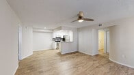 This single-floor residence offers three bedrooms and two bathrooms within a well-organized layout. The open-concept living room serves as the heart of the home, featuring light wood-look flooring, a ceiling fan with integrated lighting, a textured ceiling, and multiple windows that invite natural light. The front entry opens directly into this bright, neutral-toned living space.

The kitchen is positioned adjacent to the living area and is accessible via a peninsula-style counter with granite countertops and an undermount sink. White shaker-style cabinetry, a gray tile backsplash, and stainless steel appliances—including a refrigerator, electric range, and dishwasher—complete the kitchen's functional and contemporary aesthetic.

The bedrooms are carpeted and finished in soft neutral tones, providing a comfortable feel. The primary bedroom offers a modest but practical footprint and connects to in-unit laundry facilities. The two bathrooms differ in configuration: one includes a full tub-shower combination, while the other features a walk-in shower with a built-in seat. Wood-look flooring carries through both bathrooms, maintaining visual consistency throughout the residence.