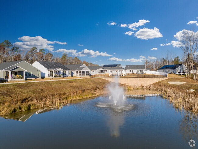 A pond with a fountain behind a quiet neighborhood.