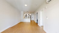 Located at 2009 Main St in Stratford, CT, this well-appointed one-bedroom, two-bathroom unit offers a clean, modern aesthetic throughout. Light bamboo-style flooring flows continuously across the entire single-floor layout, complementing neutral white and warm gray walls that create a bright, airy atmosphere.

The open-plan kitchen and living area serves as the heart of the unit. The kitchen features white shaker cabinetry, stainless steel appliances including a refrigerator, range, and over-the-range microwave, and a peninsula with pendant lighting that anchors the space. A dedicated closet area conveniently houses an in-unit washer and dryer. The living area includes a sliding glass door that opens onto a private balcony overlooking a landscaped courtyard.

The spacious primary bedroom receives natural light through a window and is equipped with a wall-mounted mini-split HVAC unit for individualized climate control. A dedicated closet provides ample storage.

Both bathrooms are finished in a clean, contemporary style. The primary bath features a long double-vanity with white cabinetry, matte black hardware, a large mirror, and a tiled shower enclosure. The second bathroom includes a single vanity and a tiled shower/tub combination with a window for natural light.