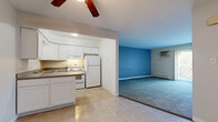 Located at 646 S York Rd in Bensenville, Illinois, this single-floor unit offers a practical and functional layout designed for comfortable everyday living. The open-concept kitchen flows directly into the living area, creating a connected and versatile space. The kitchen is equipped with white cabinetry, granite-style laminate countertops, a double-basin stainless steel sink, a white electric range with overhead ventilation, and a full-size refrigerator. Tile flooring runs throughout the kitchen, while the adjacent living area transitions to soft carpeting and features a wall-mounted air conditioning unit and a ceiling fan for year-round climate control. A sliding glass door opens to a private balcony, bringing in natural light and views of surrounding greenery. The bedrooms are carpeted and neutral in tone, each offering closet space and windows with outdoor views. Baseboard heating is present throughout the living areas and bedrooms. The bathroom includes a tiled tub-shower combination, a vanity with under-sink storage, a mirrored medicine cabinet, and tile flooring. Overall, the unit presents a clean, straightforward design suited for a range of occupants.