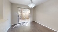 Located at 213 Argonaut Dr in El Paso, TX, this two-story, 2-bedroom, 2-bathroom home offers a well-organized layout spread across two floors. The ground floor hosts the main living areas, including a galley-style kitchen outfitted with dark cabinetry, light countertops, a peninsula with additional counter space, black appliances including a range and refrigerator, and a double sink. Track lighting and a window overlooking the exterior keep the kitchen bright. Adjacent to the kitchen is a dedicated dining area featuring dark hardwood-style flooring, a pendant light fixture, and a sliding glass door that opens to a private outdoor patio surrounded by a wood and stone fence. A full bathroom on this level includes a tiled tub-shower combination. The upper floor is home to both bedrooms, each carpeted and equipped with ceiling fans and windows with vertical blinds that allow natural light. The primary bedroom is a comfortable size with a standard closet. The second bedroom is similarly appointed. A hallway connects the upstairs rooms, and a second bathroom features a vanity with dark cabinetry, a framed mirror, and well-lit surroundings. A staircase connects the two levels, completing this efficiently designed home.