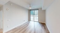 Located in the heart of uptown Charlotte, this well-appointed one-bedroom, one-bathroom unit offers a refined urban living experience with contemporary finishes throughout. The open-concept kitchen and living area serves as the heart of the home, featuring light hardwood flooring, recessed lighting, and globe pendant lights that add a modern touch. The kitchen is equipped with stainless steel appliances including a French door refrigerator, electric range, and built-in microwave, all complemented by sleek white cabinetry, quartz-style countertops, and a central island with an undermount sink. The living area extends to a private balcony through floor-to-ceiling sliding glass doors, framing impressive views of the Charlotte skyline and allowing natural light to pour in. A ceiling fan adds comfort to this bright, airy space. The bedroom is carpeted and features a large window with additional city views. The full bathroom offers a dual-sink vanity with neutral stone countertops, modern fixtures, large tile flooring, and direct access to a spacious walk-in closet outfitted with dark wood shelving, hanging rods, and built-in storage — providing ample organization for everyday living.